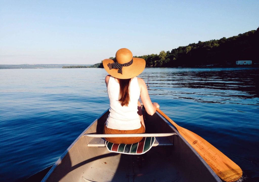 paddleboarding, picture from the boat showing woman paddleboarding and wearing beautiful hat